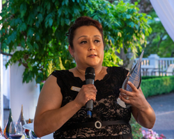 A woman holds a microphone and accepts an award