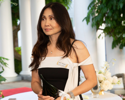 A woman smiles coyly as she accepts an award. She has dark hair past her shoulders.