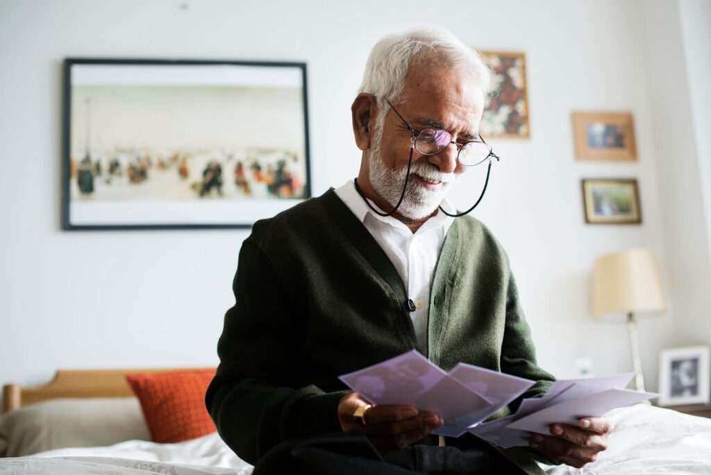 an elderly man with glasses smiles as he checks the mail in Assisted Living, Oceanside CA
